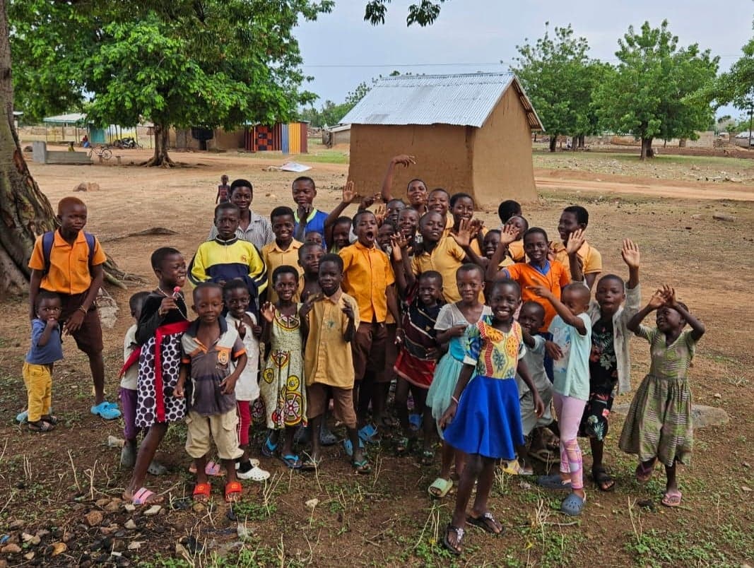 A group of children waving in front of their school